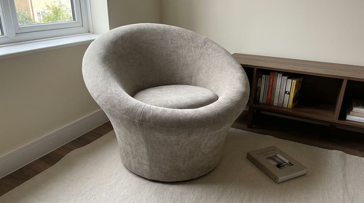 Beige-gray sculptural lounge chair beside a low wooden bookshelf