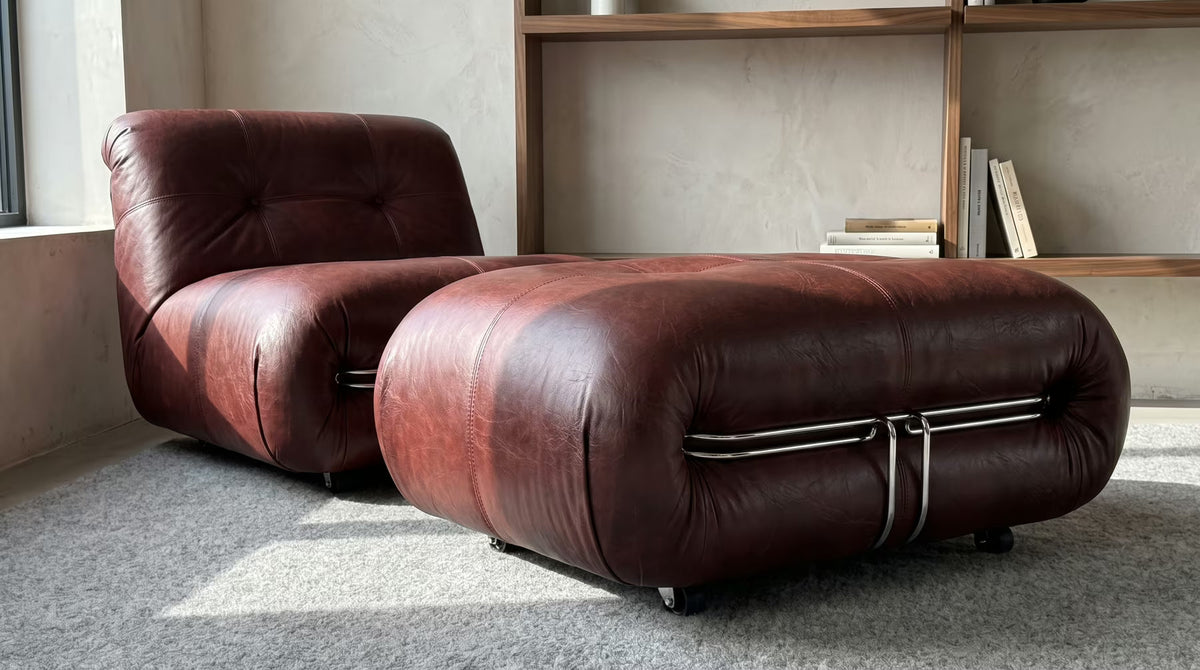 Oxblood upholstered ottoman beside a matching lounge chair
