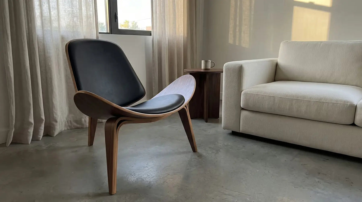 Walnut shell lounge chair beside an ivory sofa