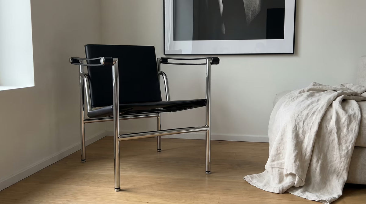 Black upholstered lounge chair with an exposed polished tubular frame