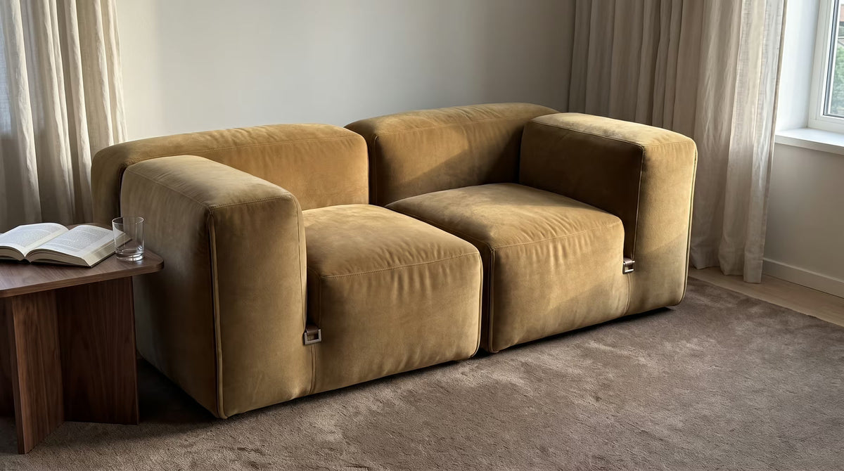 Old-gold velvet two-seater sofa beside a wooden side table